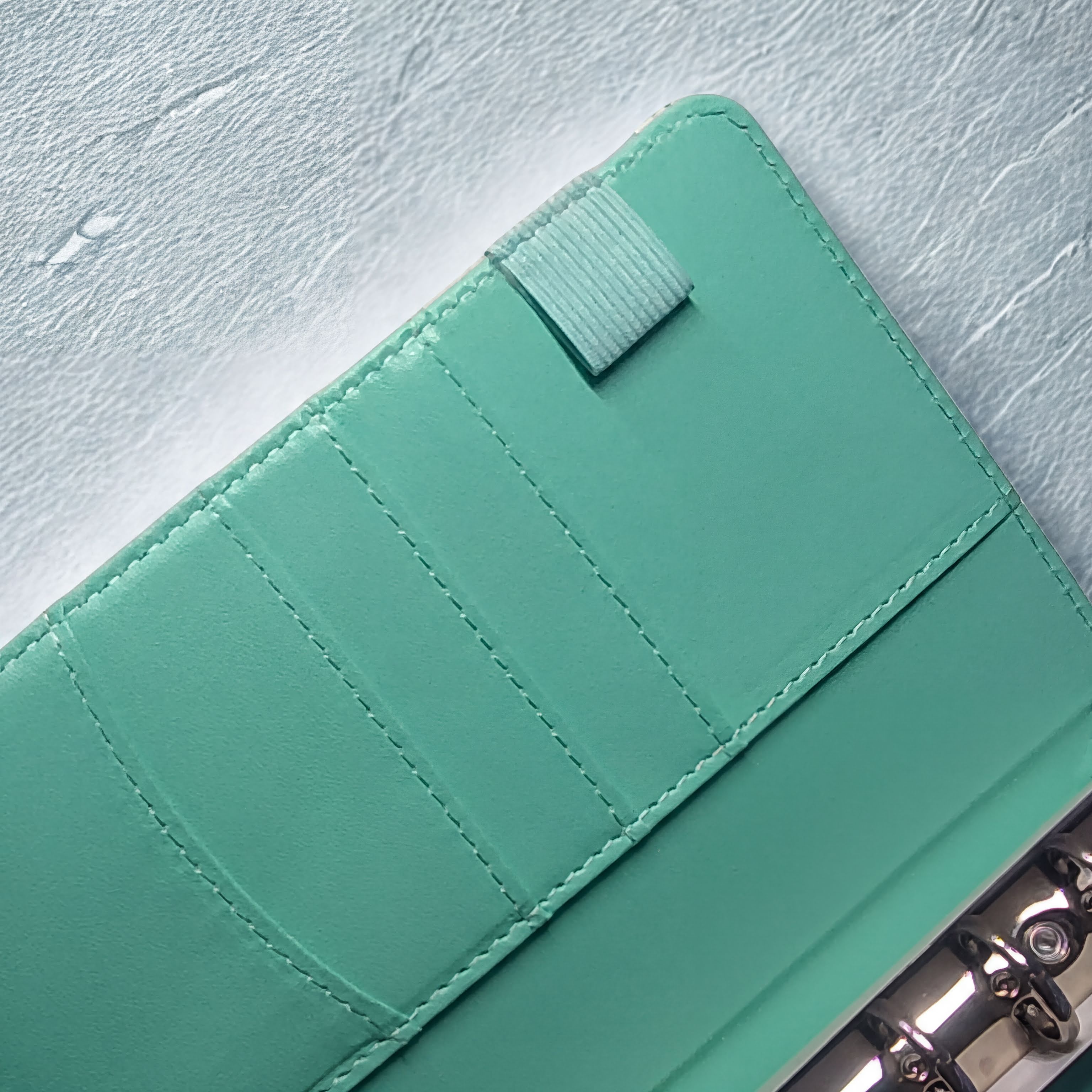 Mint green leather wallet with card slots and snap closure on textured white surface