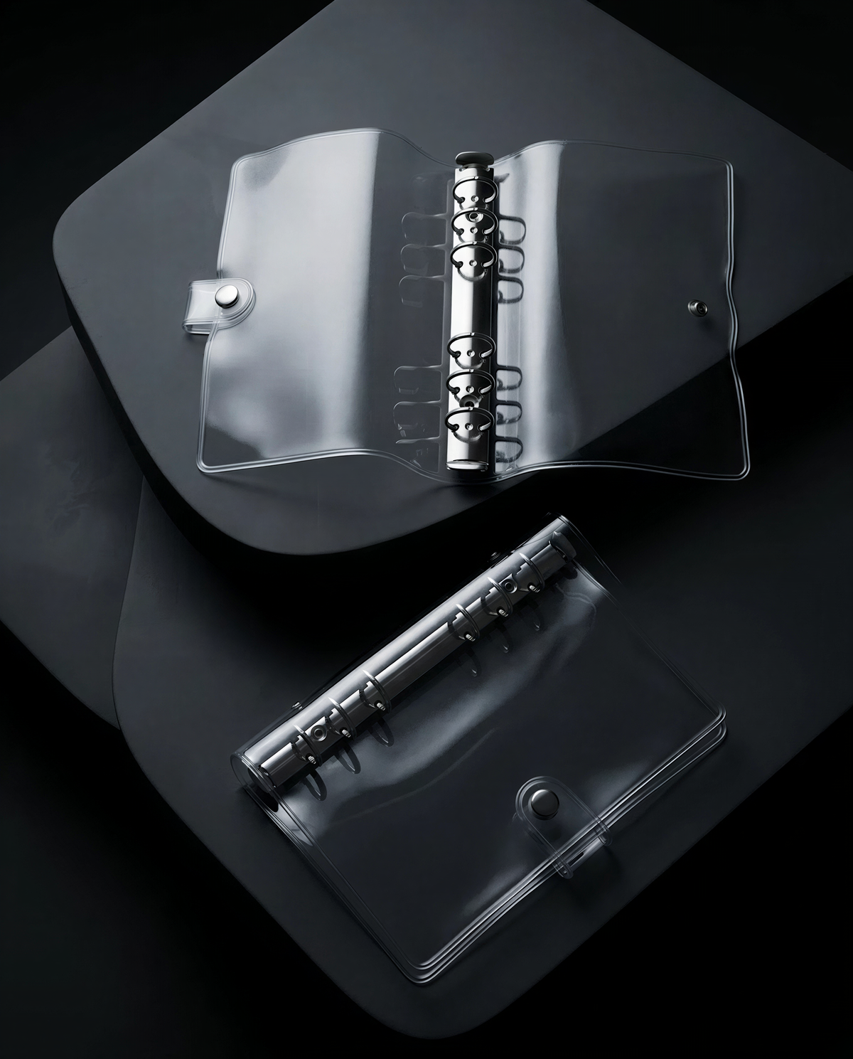 a transparent plastic binder with metal rings, placed on a dark surface.