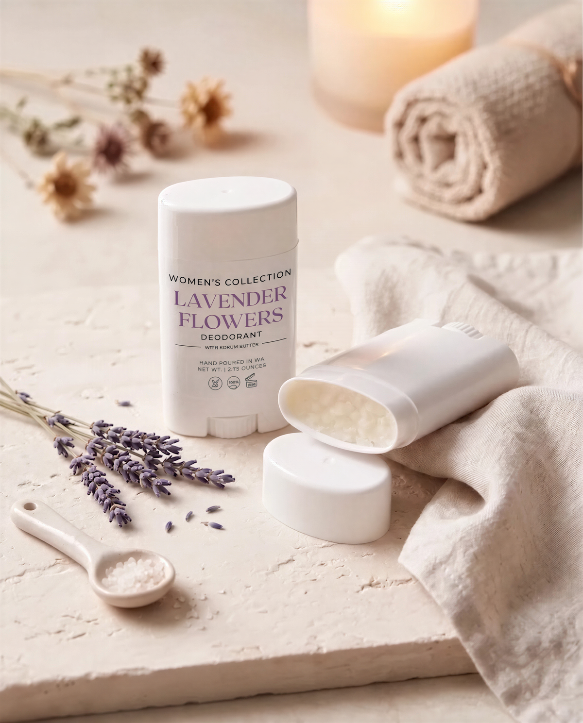 a collection of items related to personal care, including a deodorant stick, a rolled-up towel, and some dried lavender flowers.