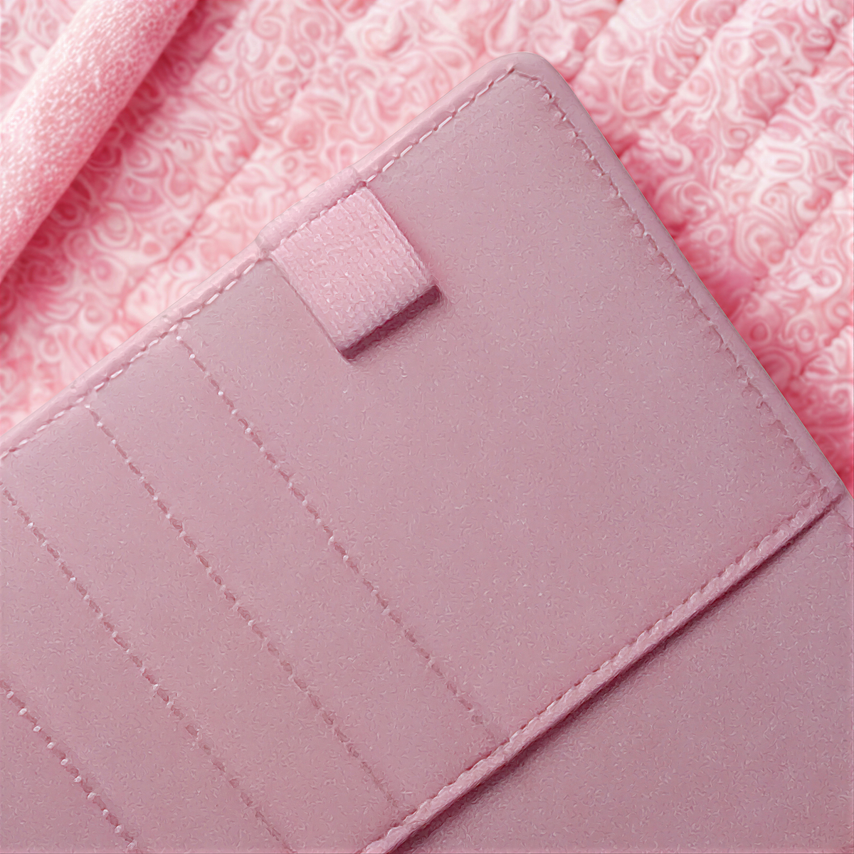 Pink quilted soap bar with textured surface and stitched edges, resting on patterned fabric