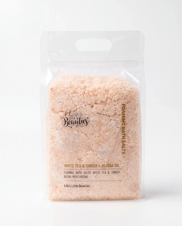A clear plastic bag containing a pinkish-white powder substance, which appears to be a bath salt product. The bag has a handle and is labeled with text that describes the product.