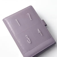 A purple leather-bound notebook or planner with numbered pages, including the numbers 1, 2, 3, and 4.