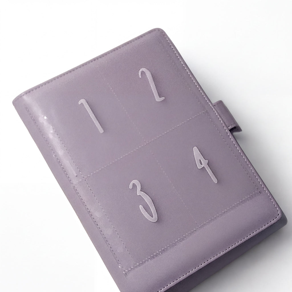 A purple leather-bound notebook or planner with numbered pages, including the numbers 1, 2, 3, and 4.