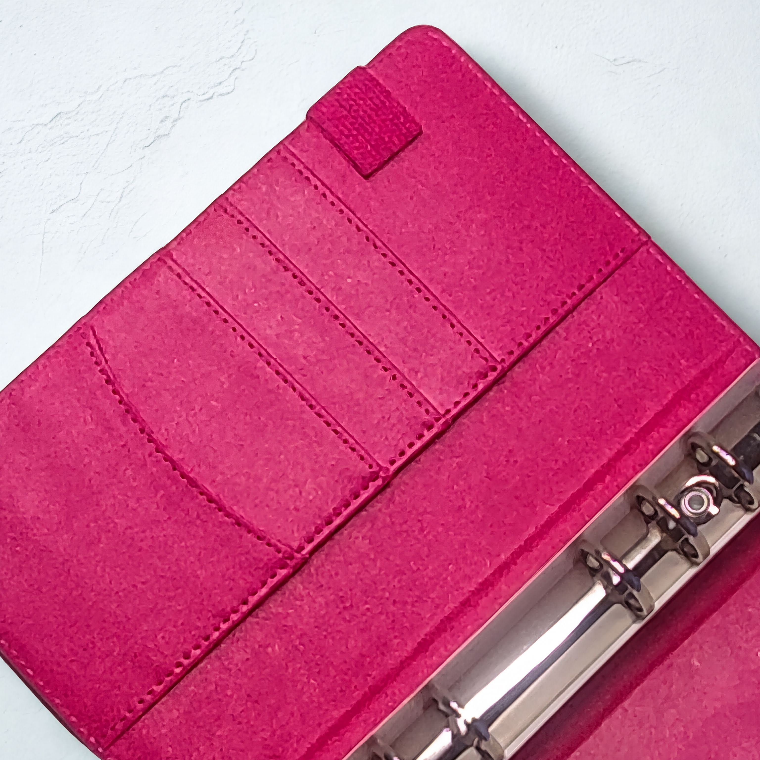 Fuchsia pink planner with card slots and metal rings, textured cover