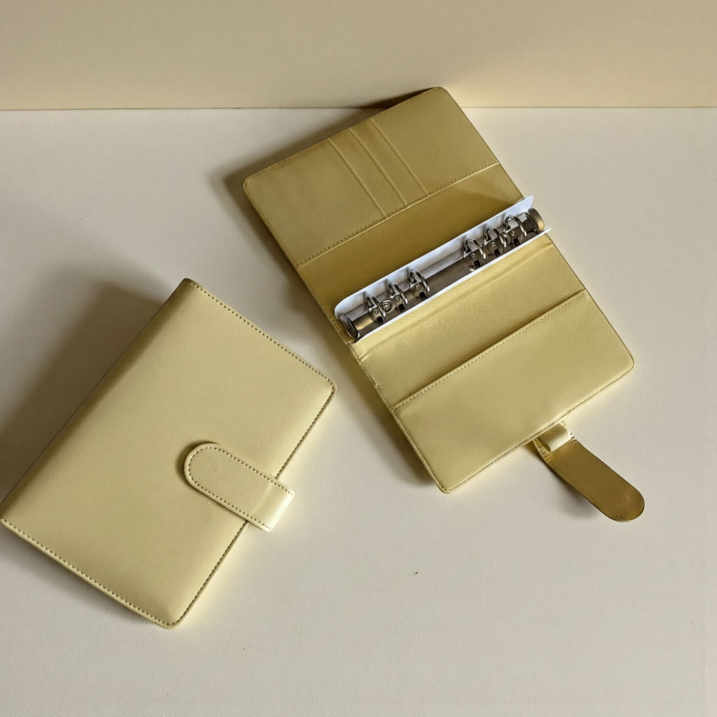 Two beige leather-bound planners or notebooks are placed on a white surface.
