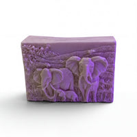 A rectangular soap bar with a carved design depicting two elephants in a grassy field.