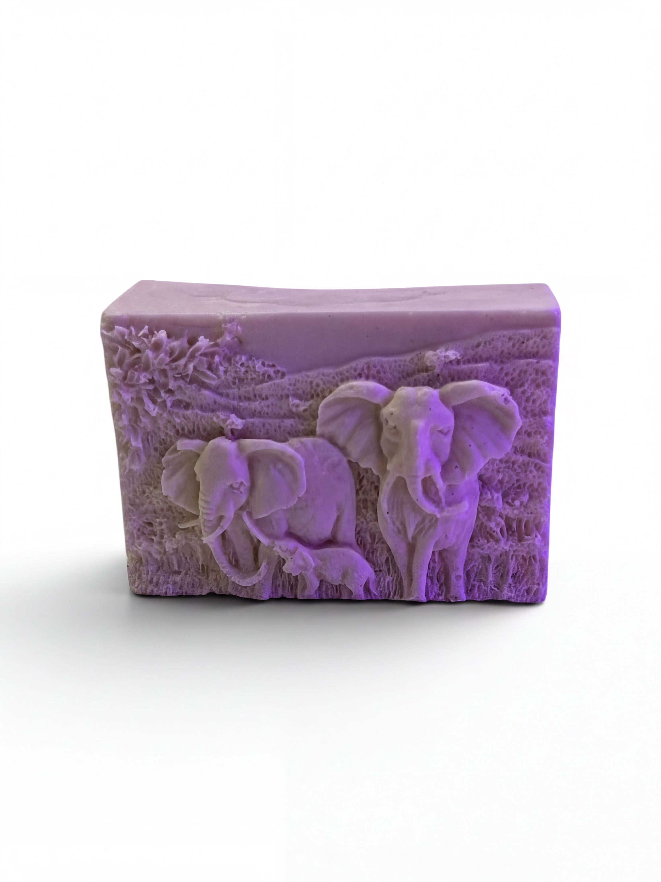 A rectangular soap bar with a carved design depicting two elephants in a grassy field.