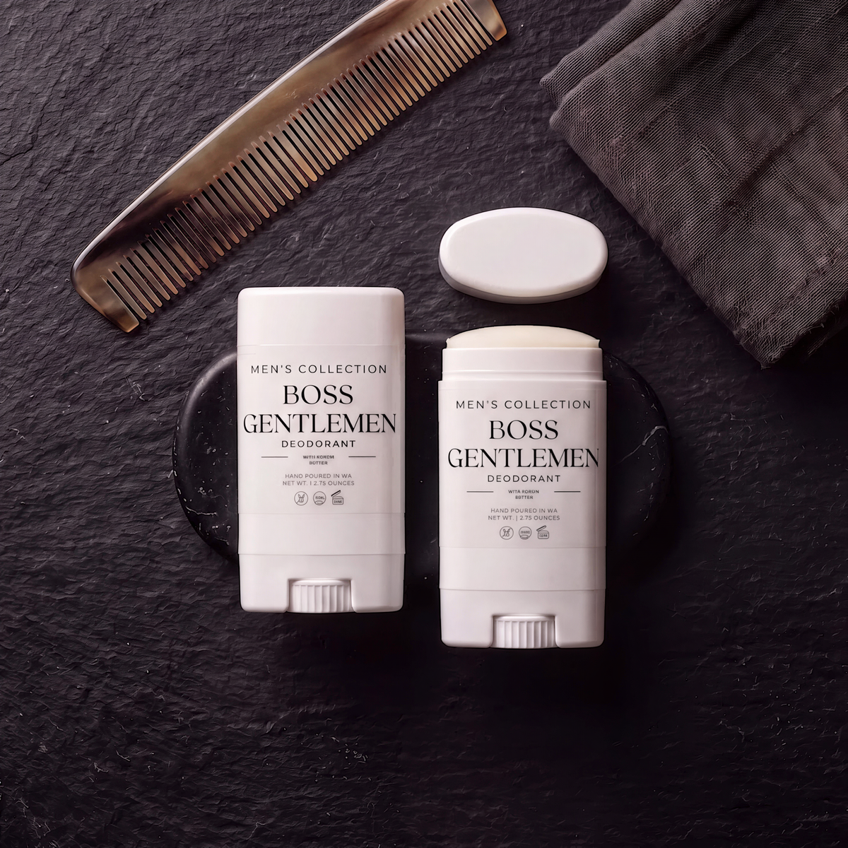 two deodorant sticks and a comb on a dark surface, along with a towel.