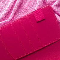 A close-up view of a vibrant pink wallet or card holder, with a small pink tag attached to it.