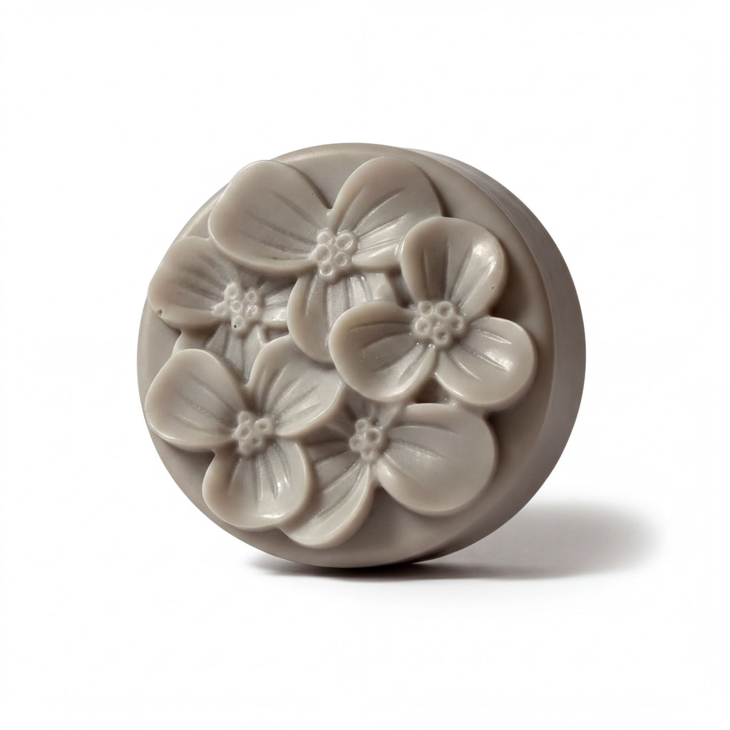 A round, gray soap bar with a floral design on it.