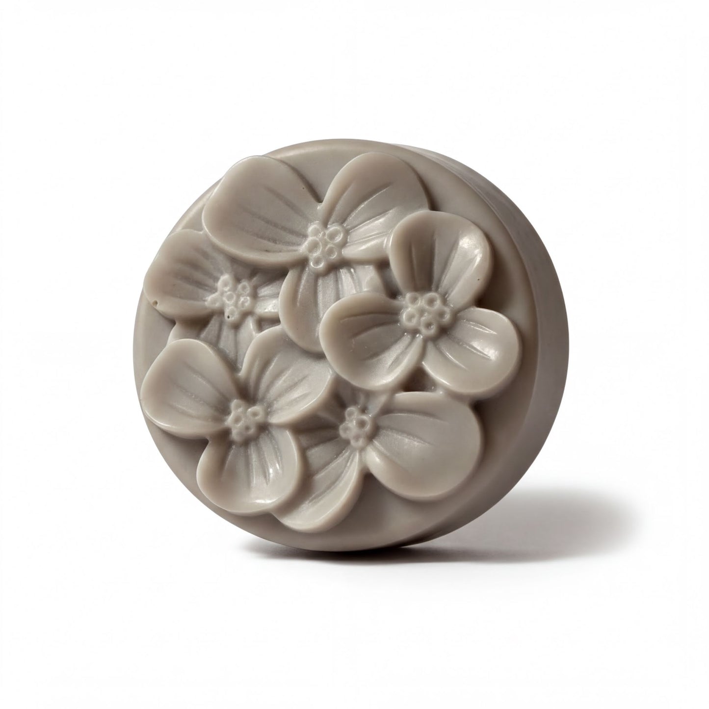A round, gray soap bar with a floral design on it.