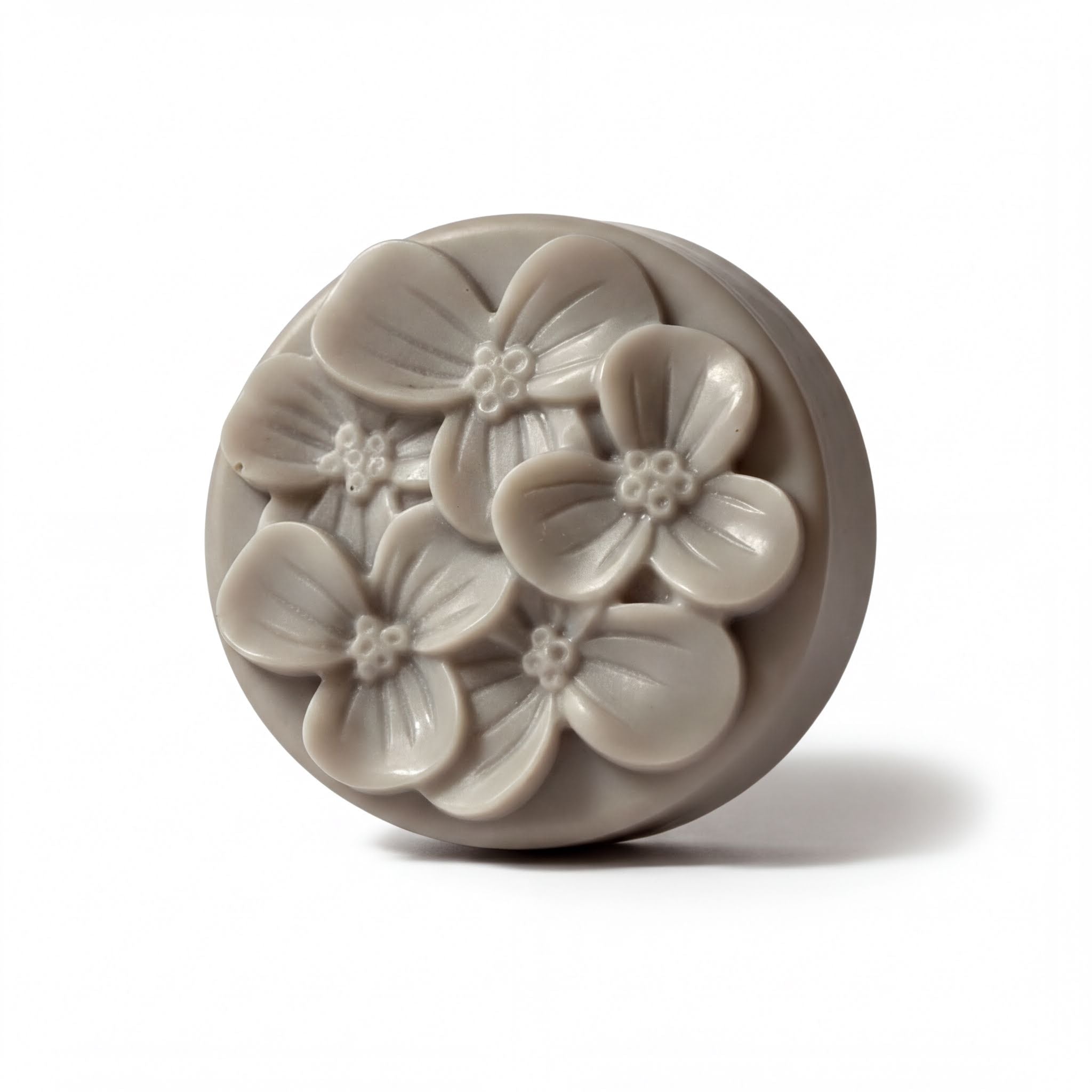 A round, gray soap bar with a floral design on it.