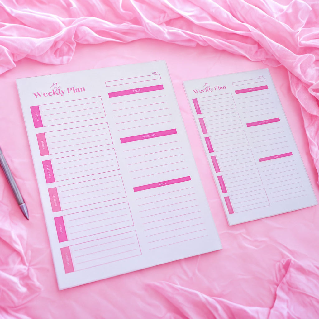 two pink planners or schedules placed on a pink fabric background.