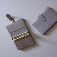 two gray leather wallets or purses placed on a light-colored surface.