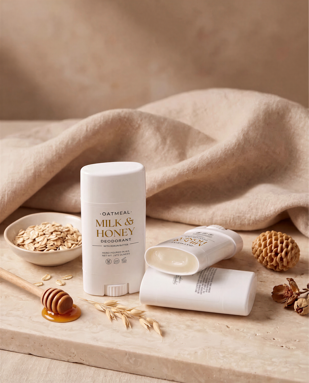 a collection of beauty products, including a tube of Oatmeal Milk & Honey Cream, a honey dipper, and a small bowl of oats, all arranged on a beige surface.
