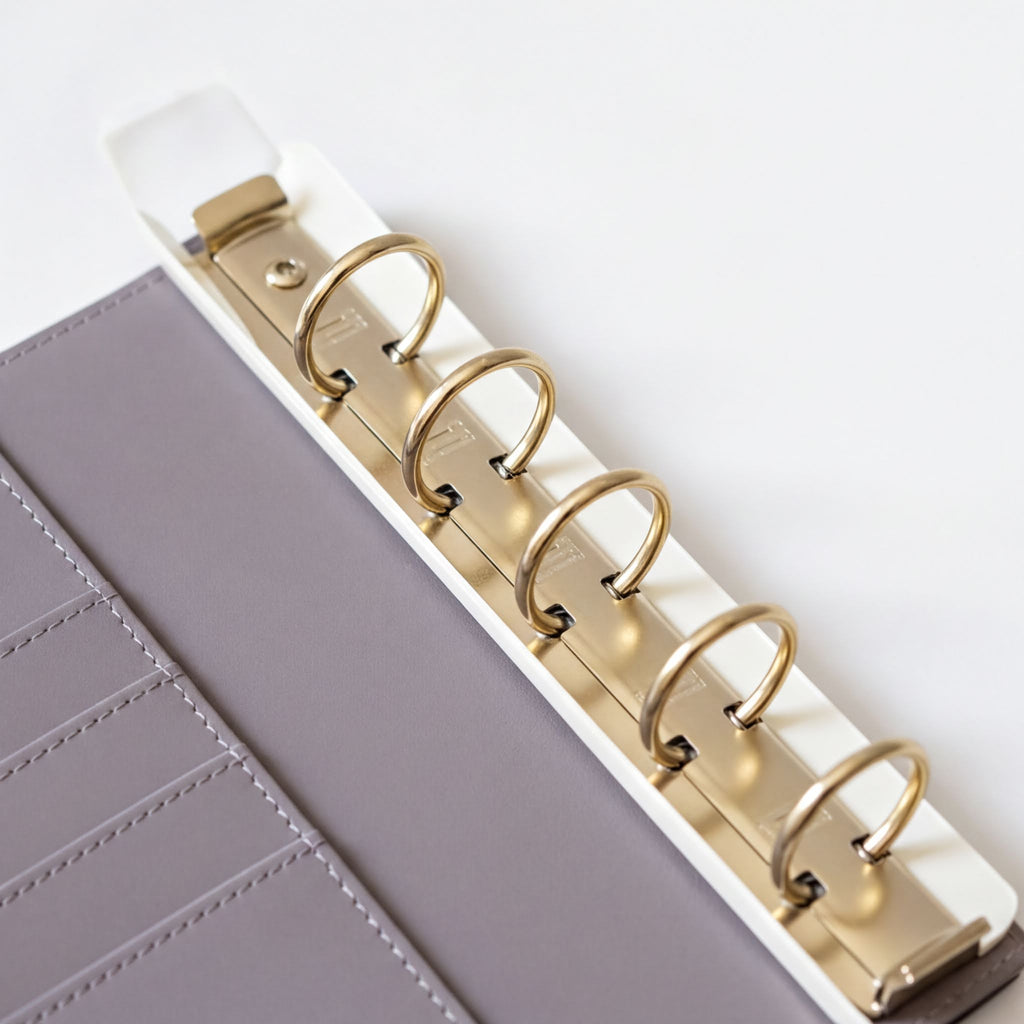 A close-up view of a spiral-bound notebook with gold rings, resting on a white surface.
