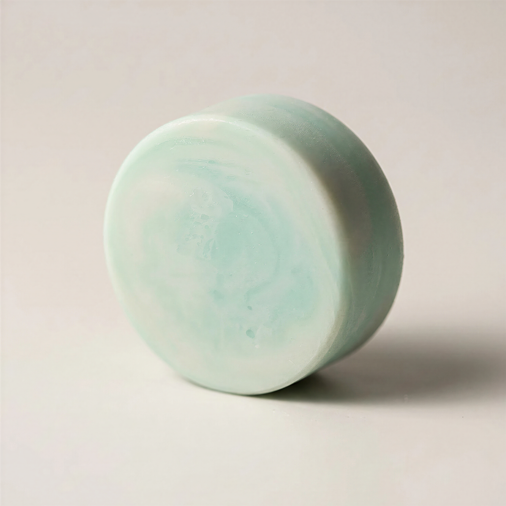 A light green, round soap bar is shown against a plain white background.