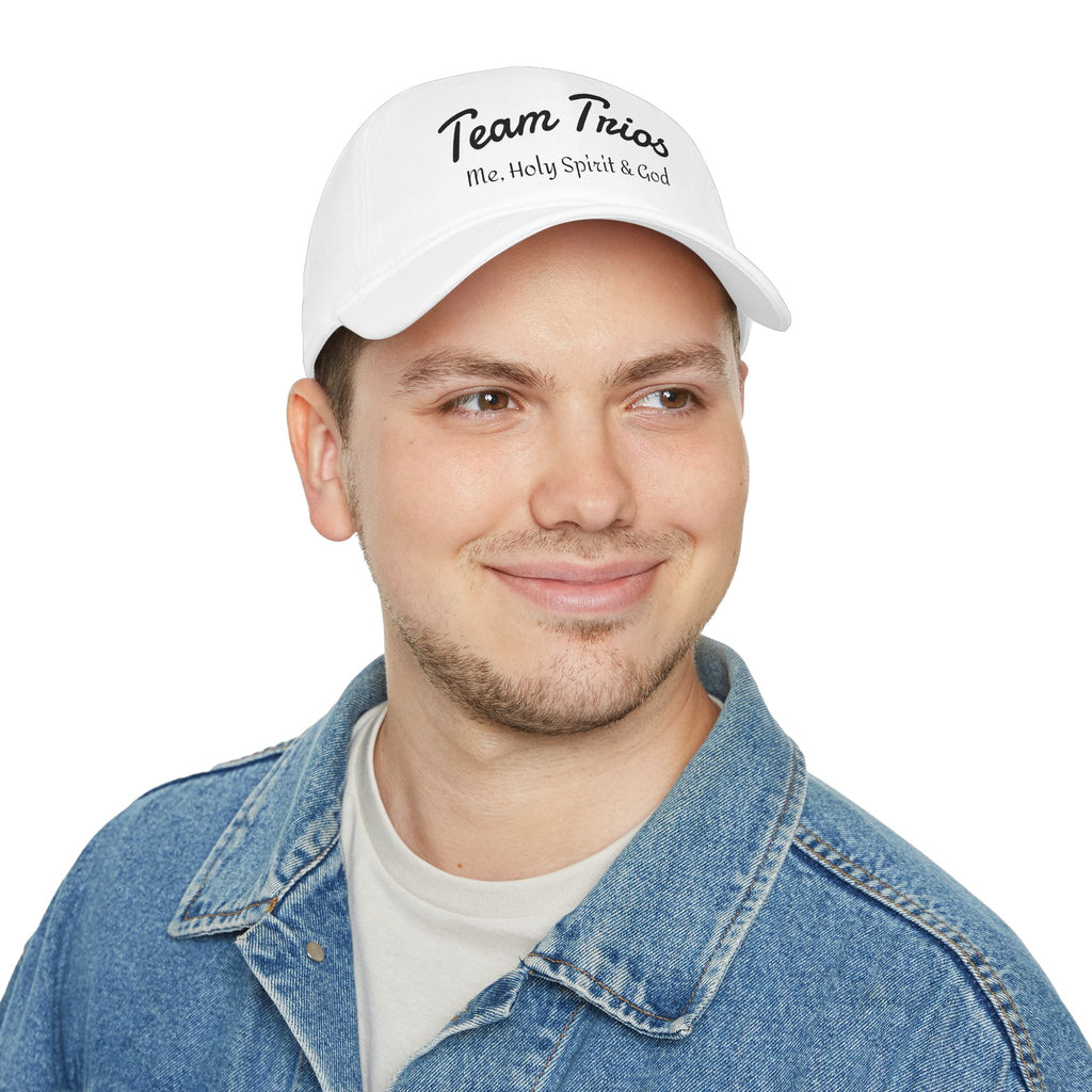White cap with 'Team Trios Me, Holy Spirit & God' text, worn by smiling man in denim jacket