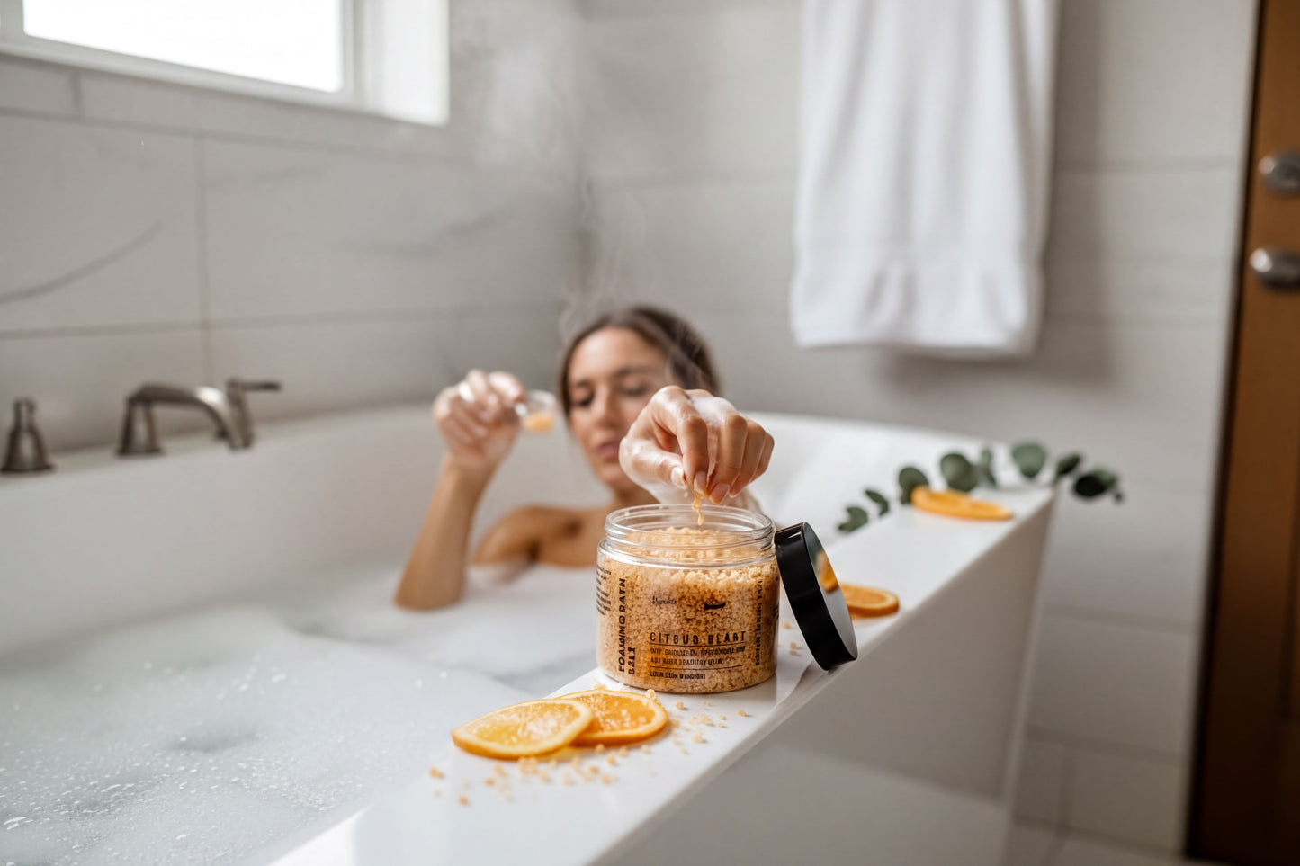 A woman is sitting in a bathtub, surrounded by orange slices and a jar of bath salt.