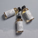 Three bottles of a brown liquid spray with black caps, arranged on a gray background.