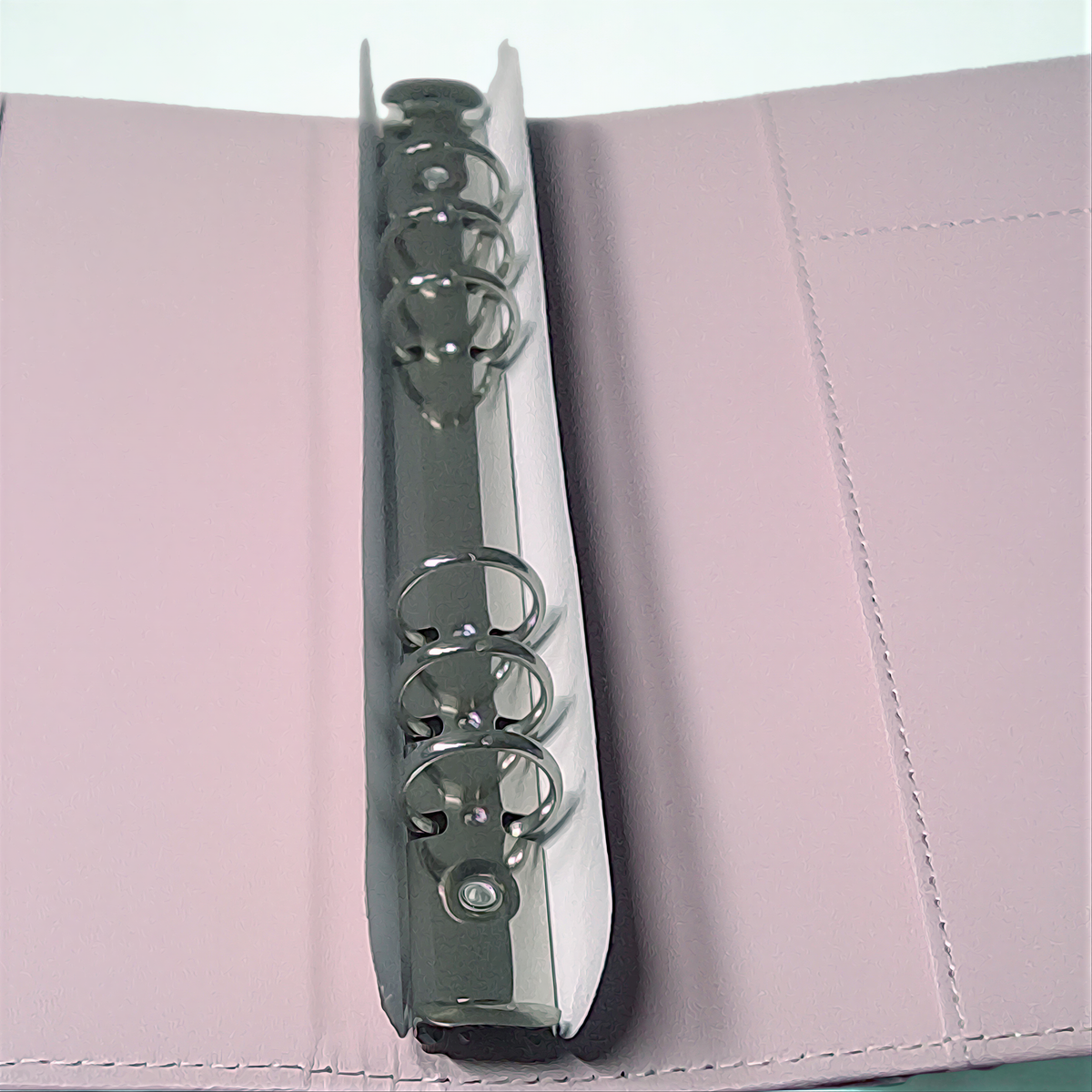 Silver decorative binder clip on textured pink surface