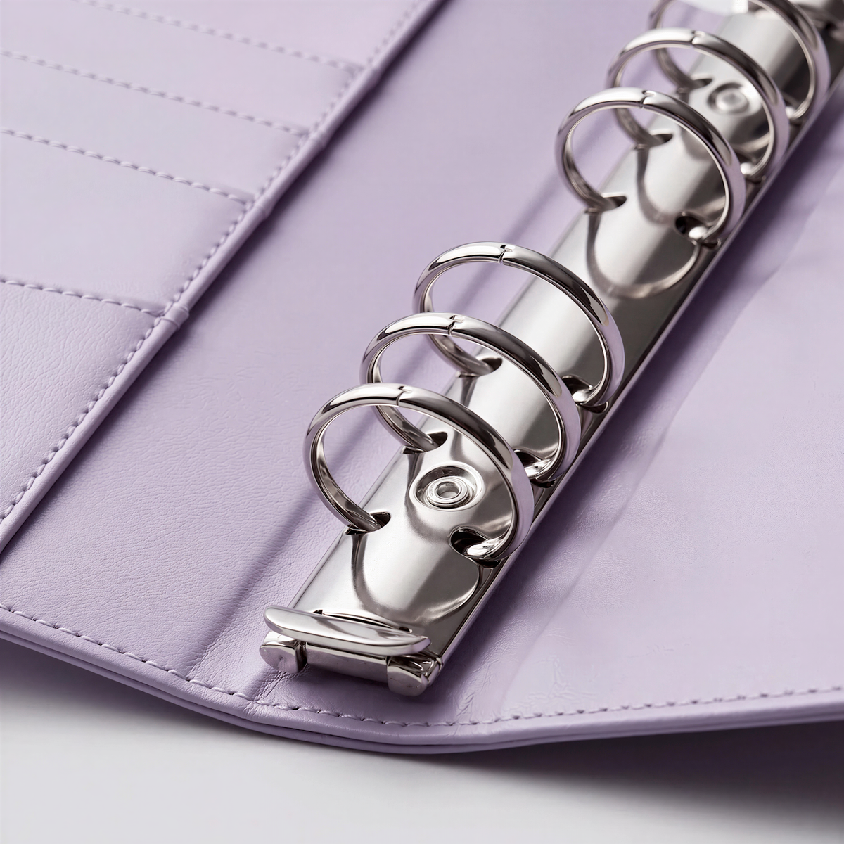 A close-up view of a silver metal ring mechanism inside a purple leather-like cover.