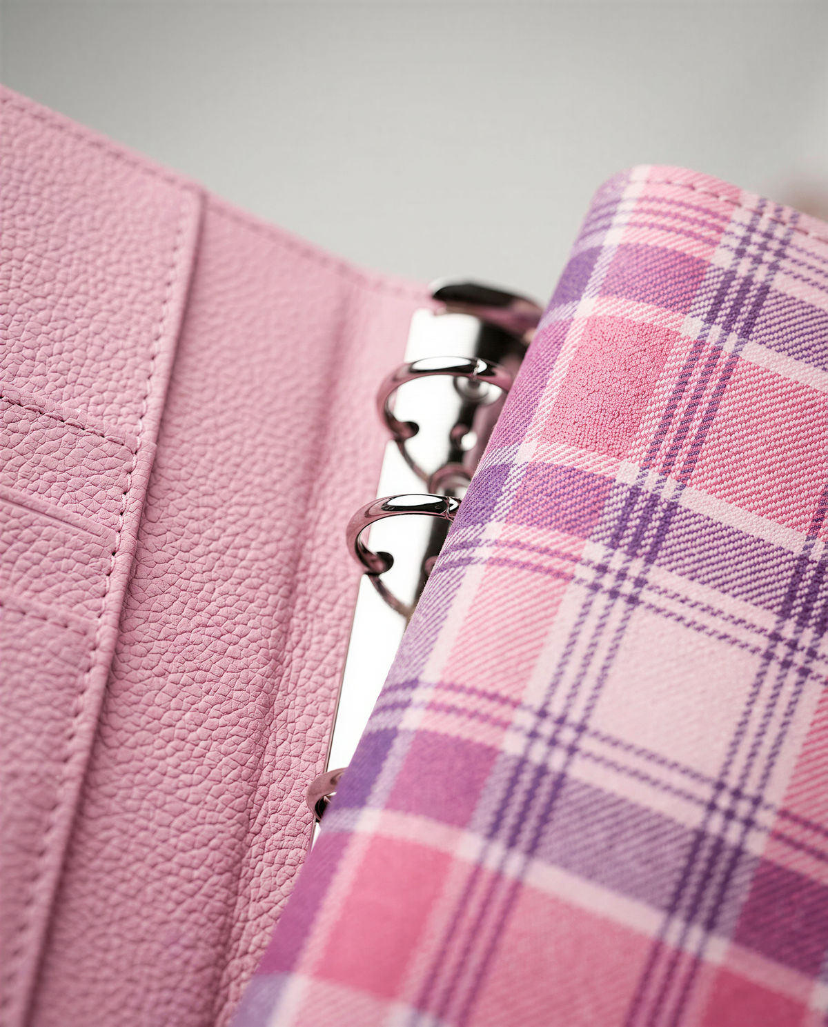 A pink leather-like wallet or purse with a plaid pattern, and a metal ring or clasp visible inside.