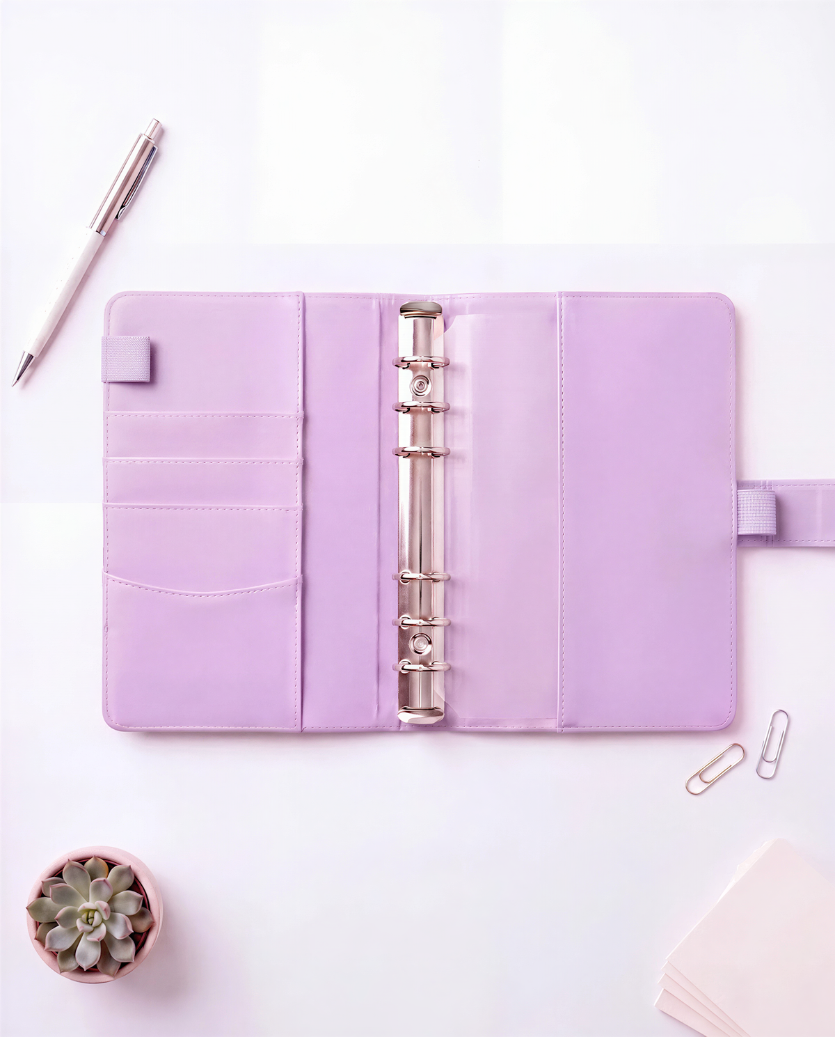 a pink binder with a pen and a small succulent plant on a white background.