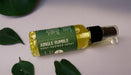 A bottle of Jungle Rumble Post-Shower Spray surrounded by green leaves on a white background.