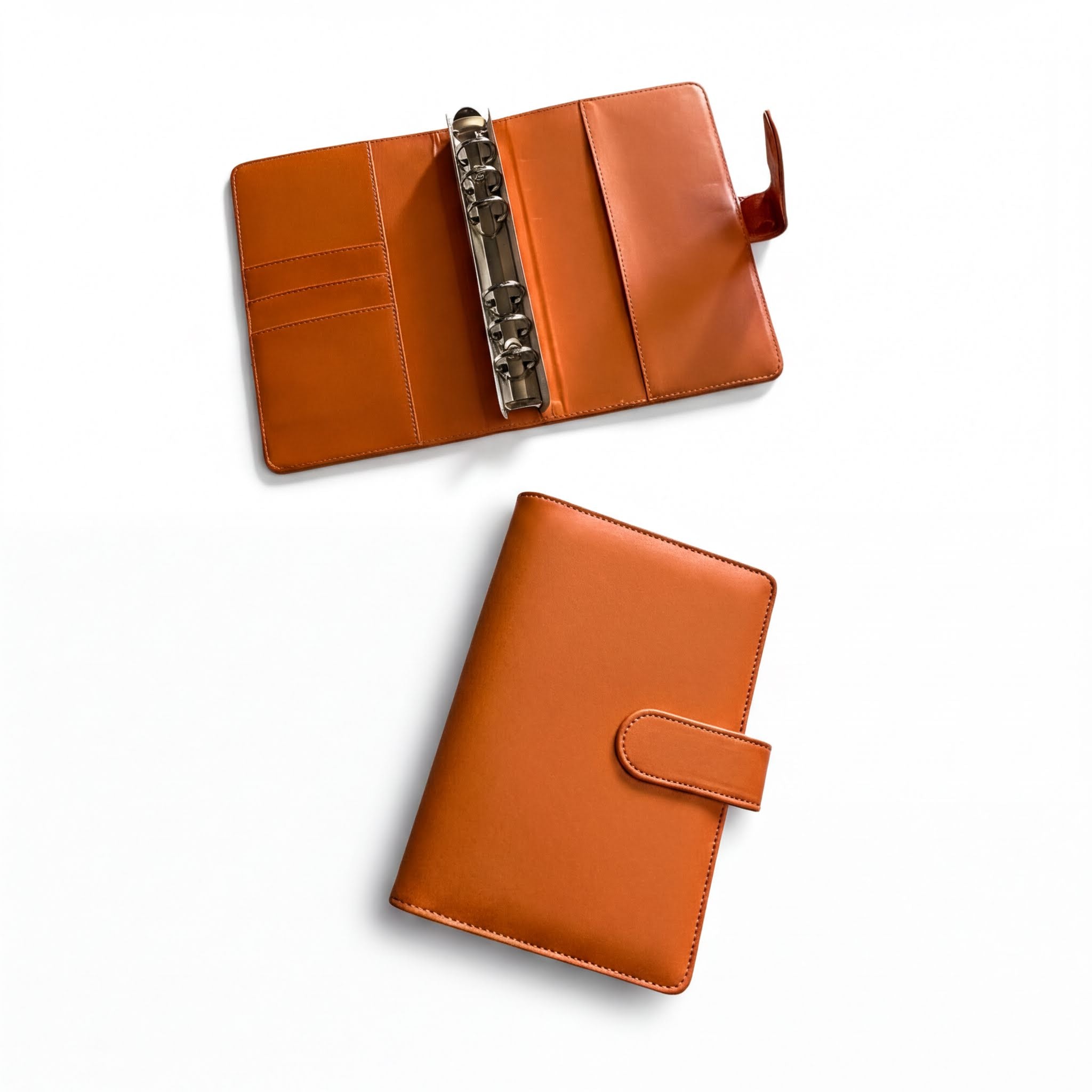 two leather-bound notebooks or planners with orange covers, one open and the other closed, placed on a white background.