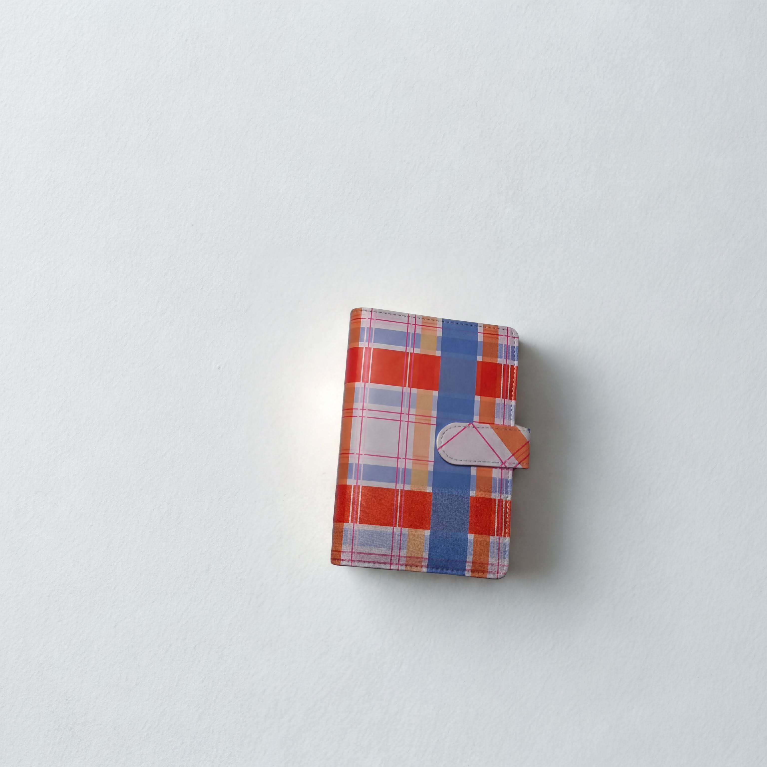 Plaid patterned wallet with orange, blue, and white check design on white background