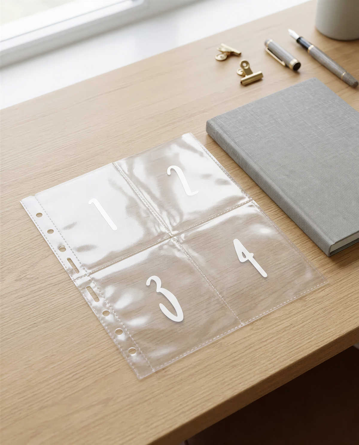 a clear plastic organizer with numbered sections on a wooden desk, along with various office supplies such as pens and a book.