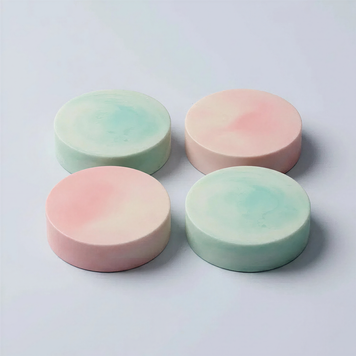 four round, colorful soap bars arranged in a square formation on a white background.