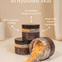 three jars of a product called "FAMOUS" with a focus on the "FAMOUS" label. The jars are filled with a mixture of orange and black ingredients, and one jar has spilled its contents onto the table. The text above the jars reads "Discover the Secret to Hydrated Skin" and below the jars, it states that the product is "An indulgent escape for just $15" and "Made with natural ingredients".