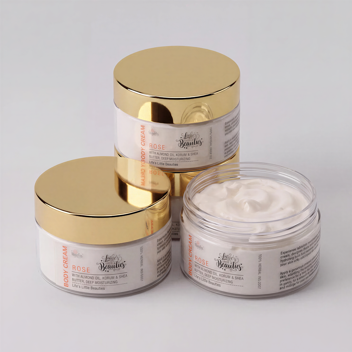 three jars of body cream with gold lids, arranged in a row.