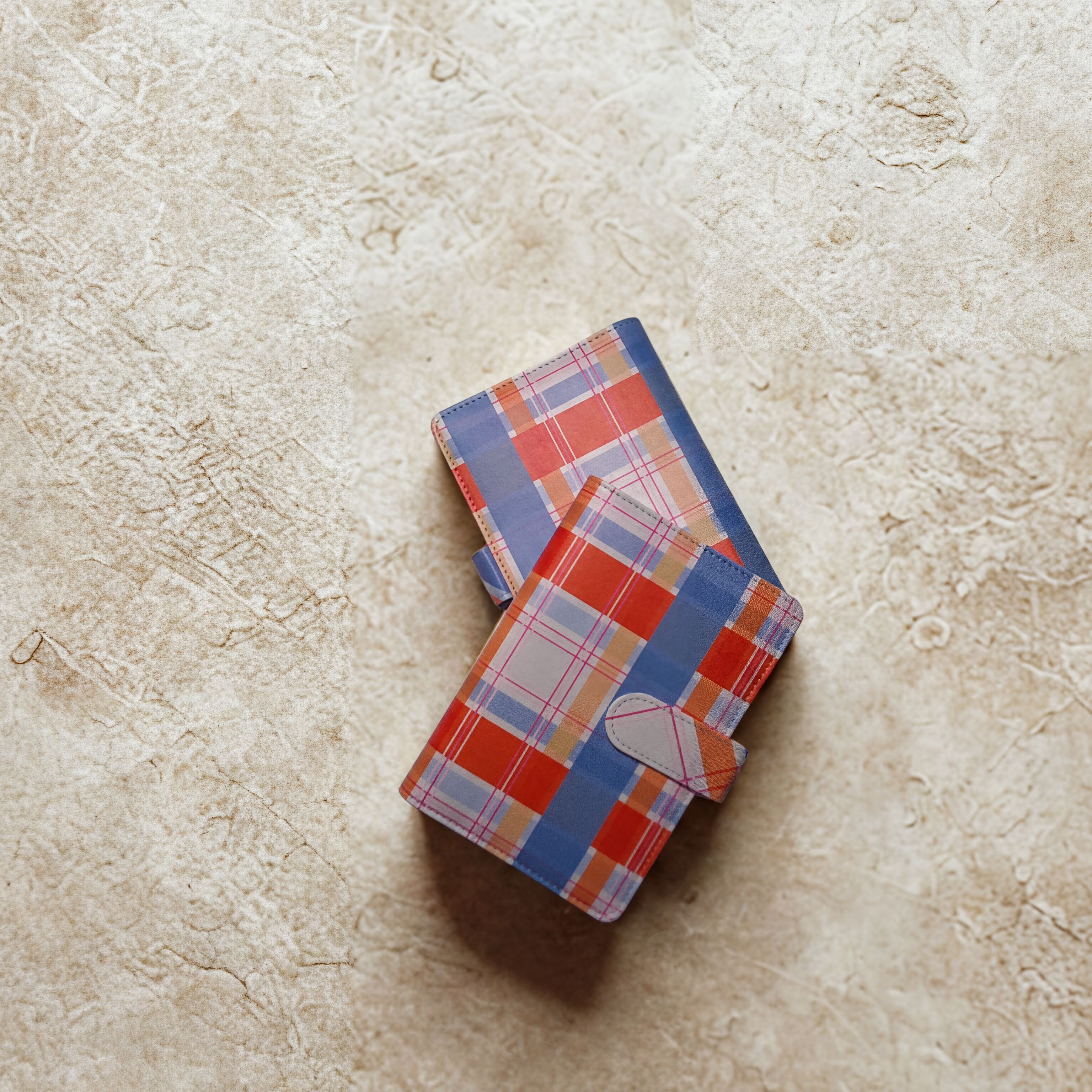 Plaid patterned wallet with blue, red, and beige tones on textured surface