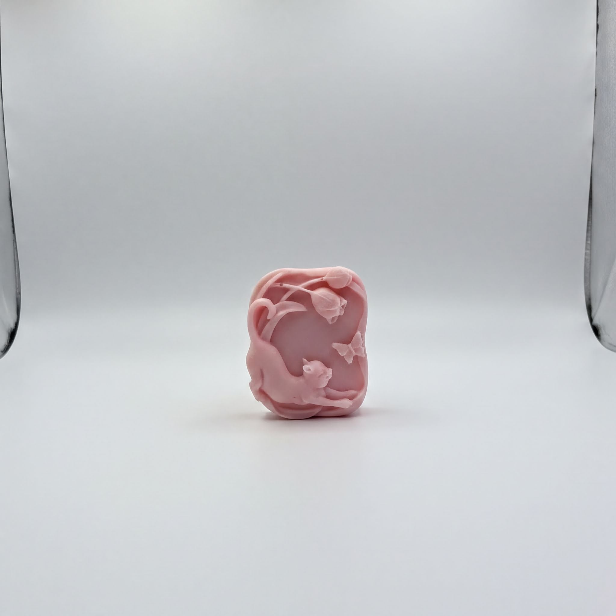 A pink soap sculpture with a floral design is centered against a white background.