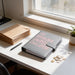 A stack of brown envelopes, a gray binder with the text 