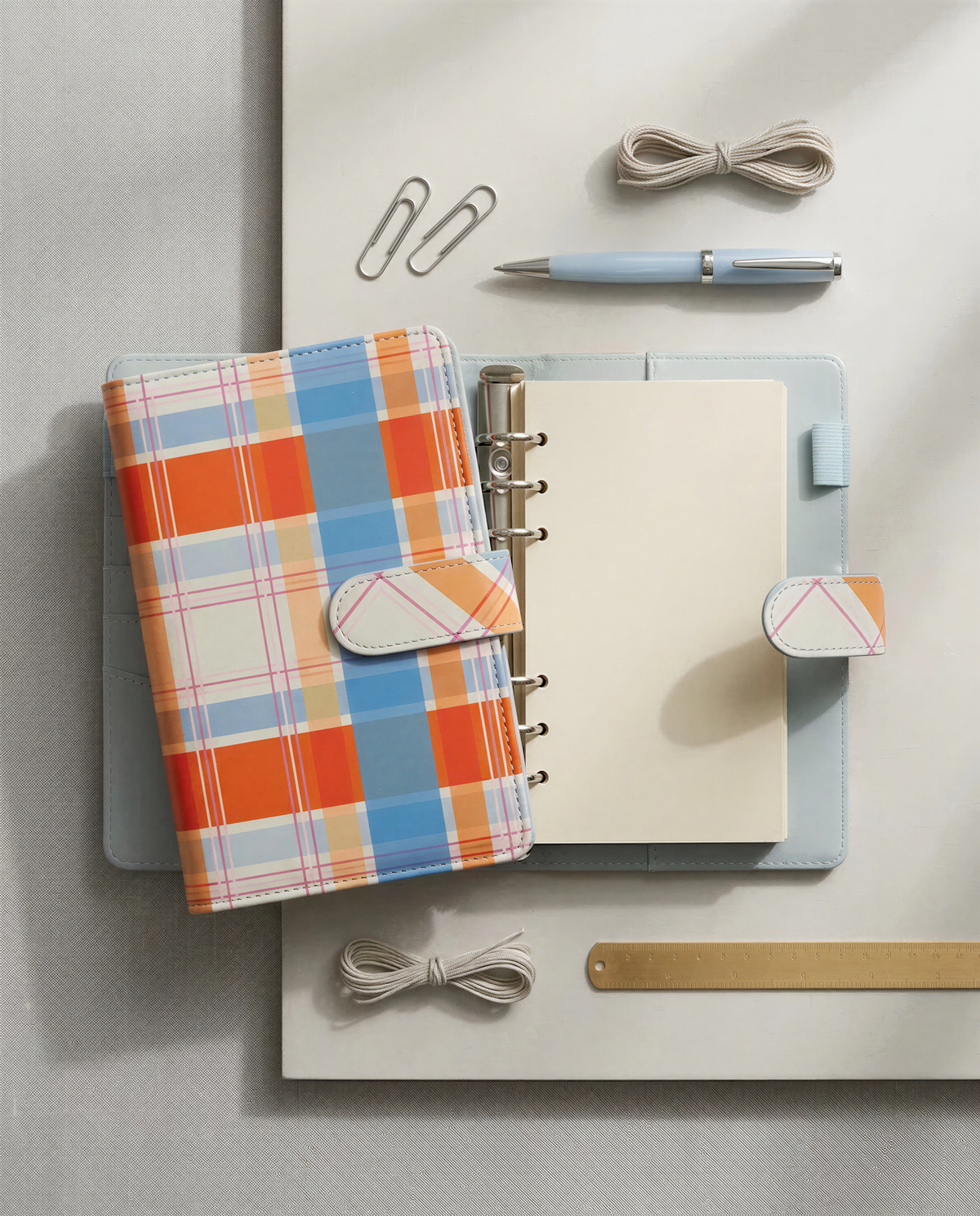 a collection of office and personal items, including a notebook, a pen, a ruler, and some office supplies, arranged on a white surface.