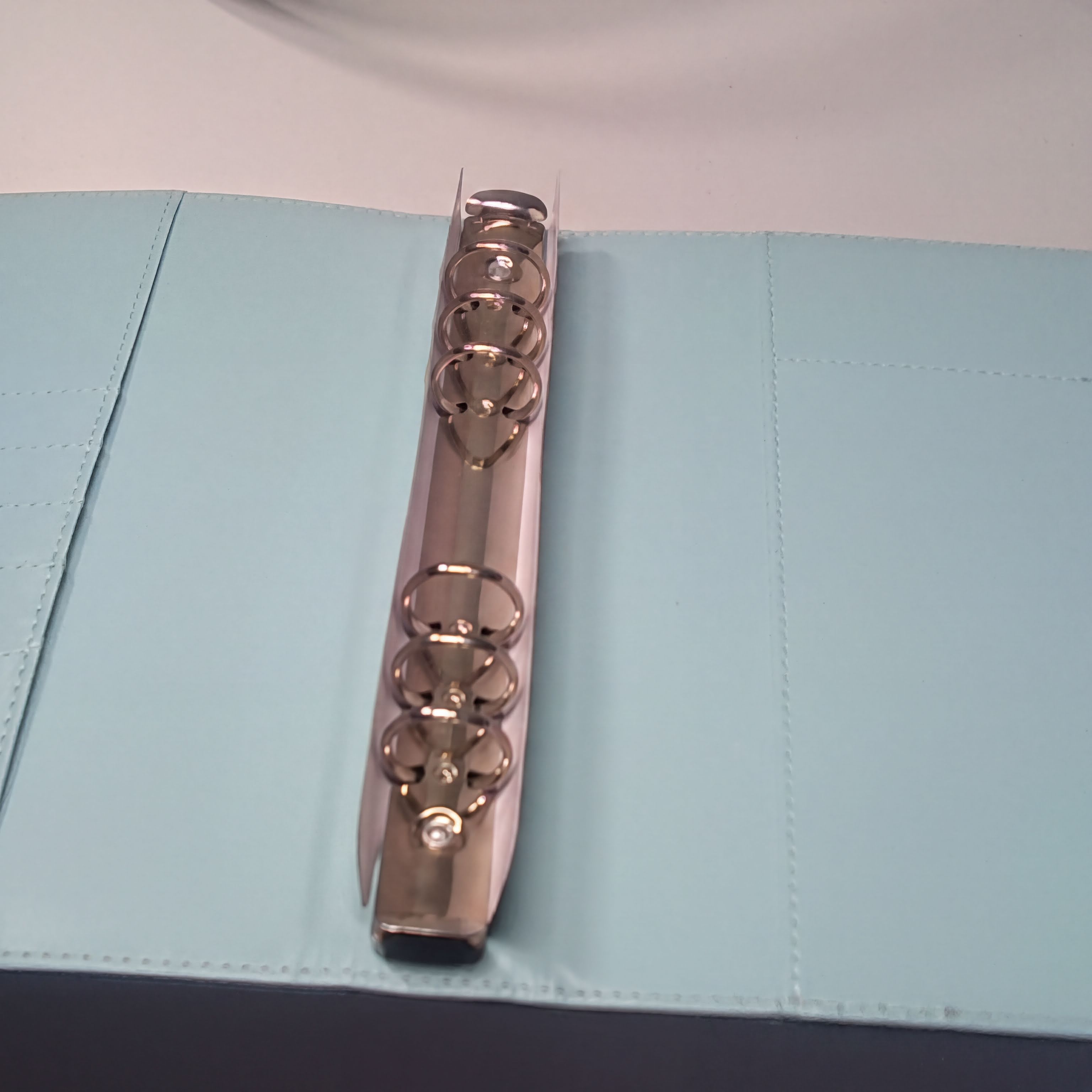 Rose gold planner binder rings on light blue faux leather cover