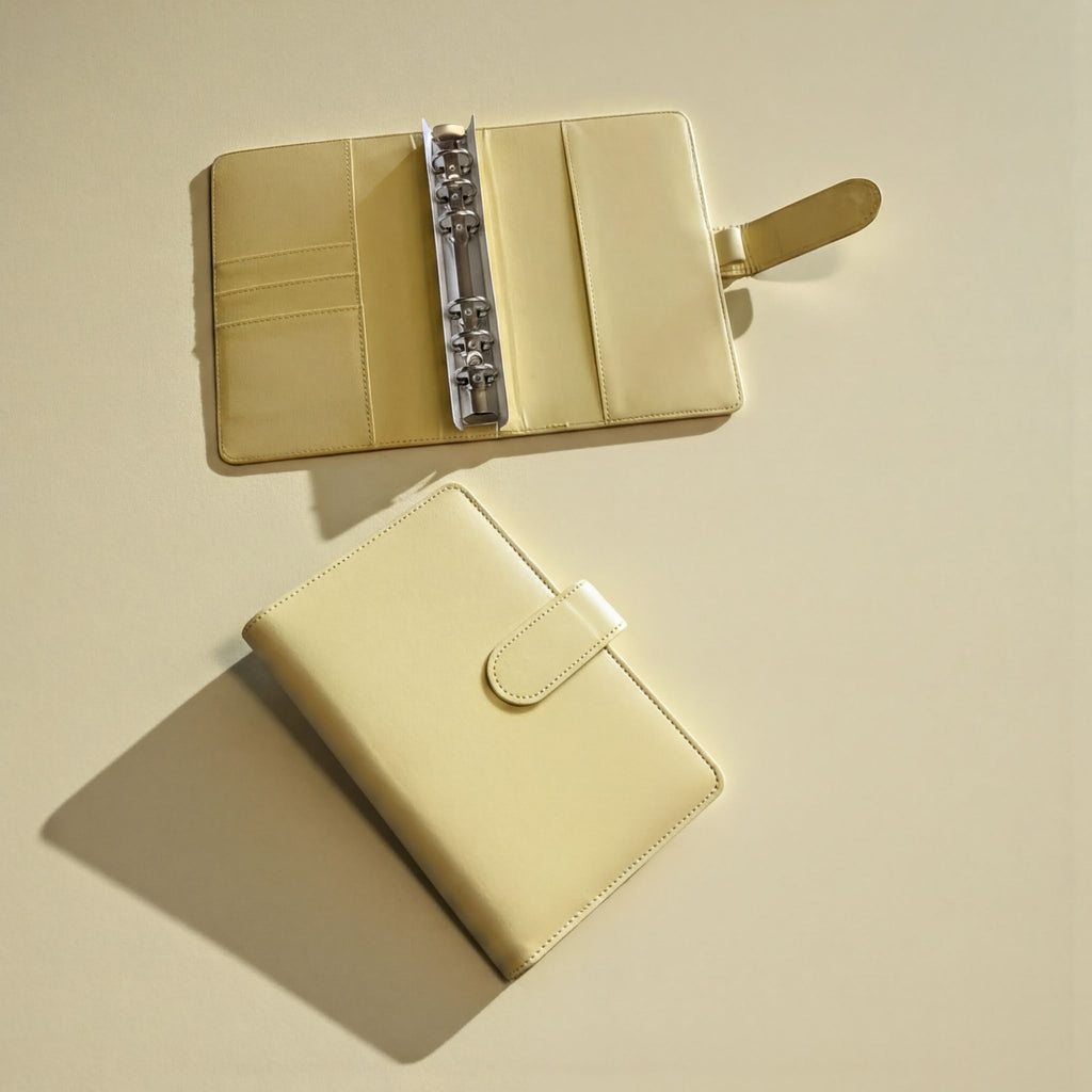 two beige leather wallets or purses placed on a light-colored surface.