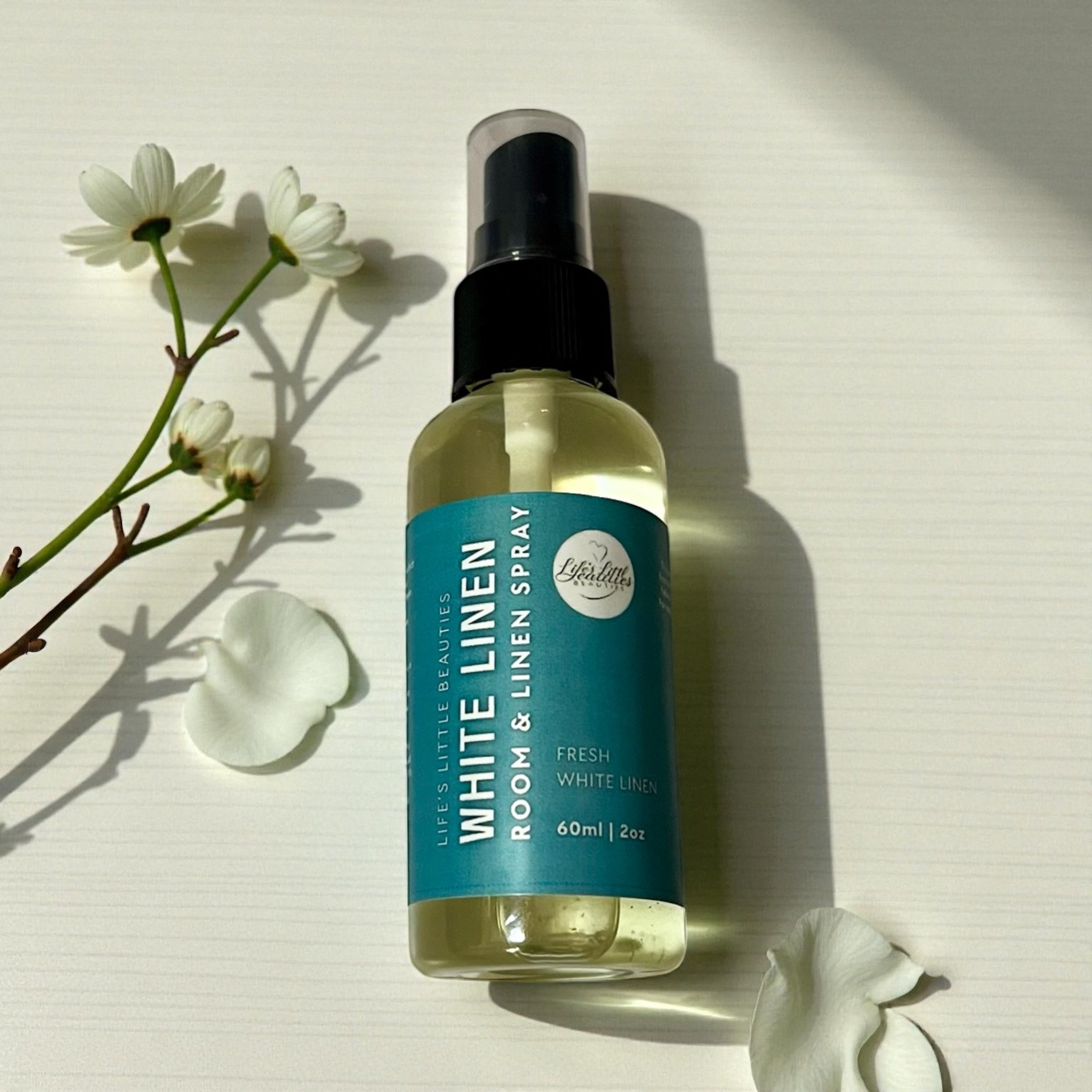 White Linen room & linen spray with natural ingredients, fresh scent, beside white flowers and petals