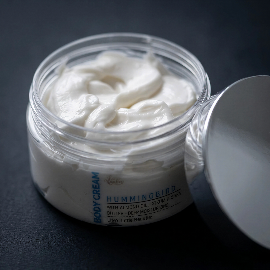 A jar of body cream with a white, creamy texture and a silver lid, placed on a dark surface.