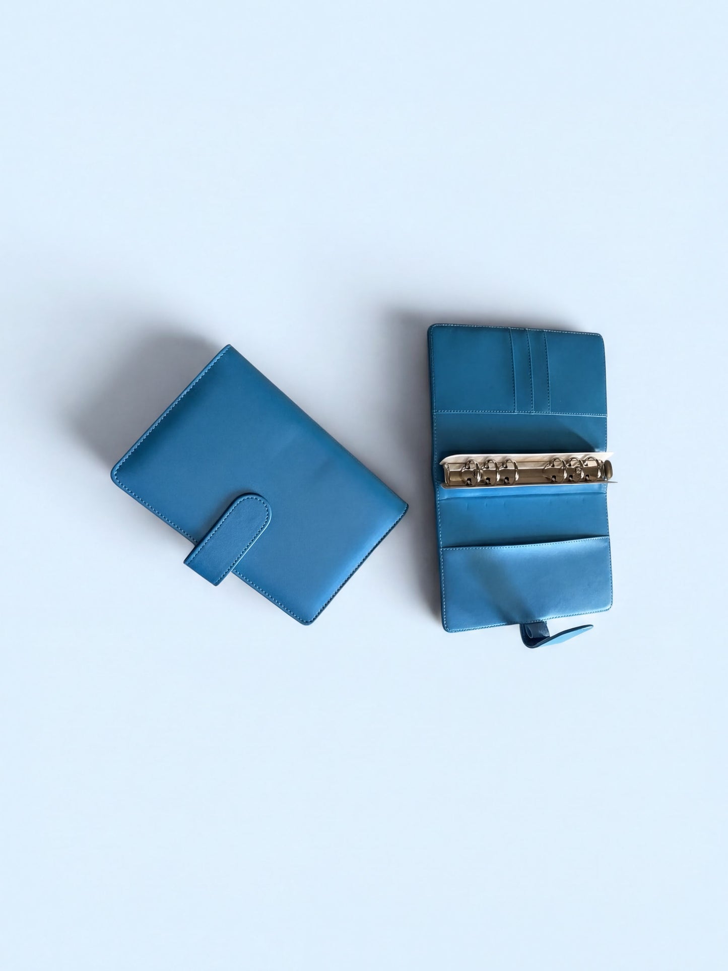 Two blue leather wallets are shown against a light blue background.