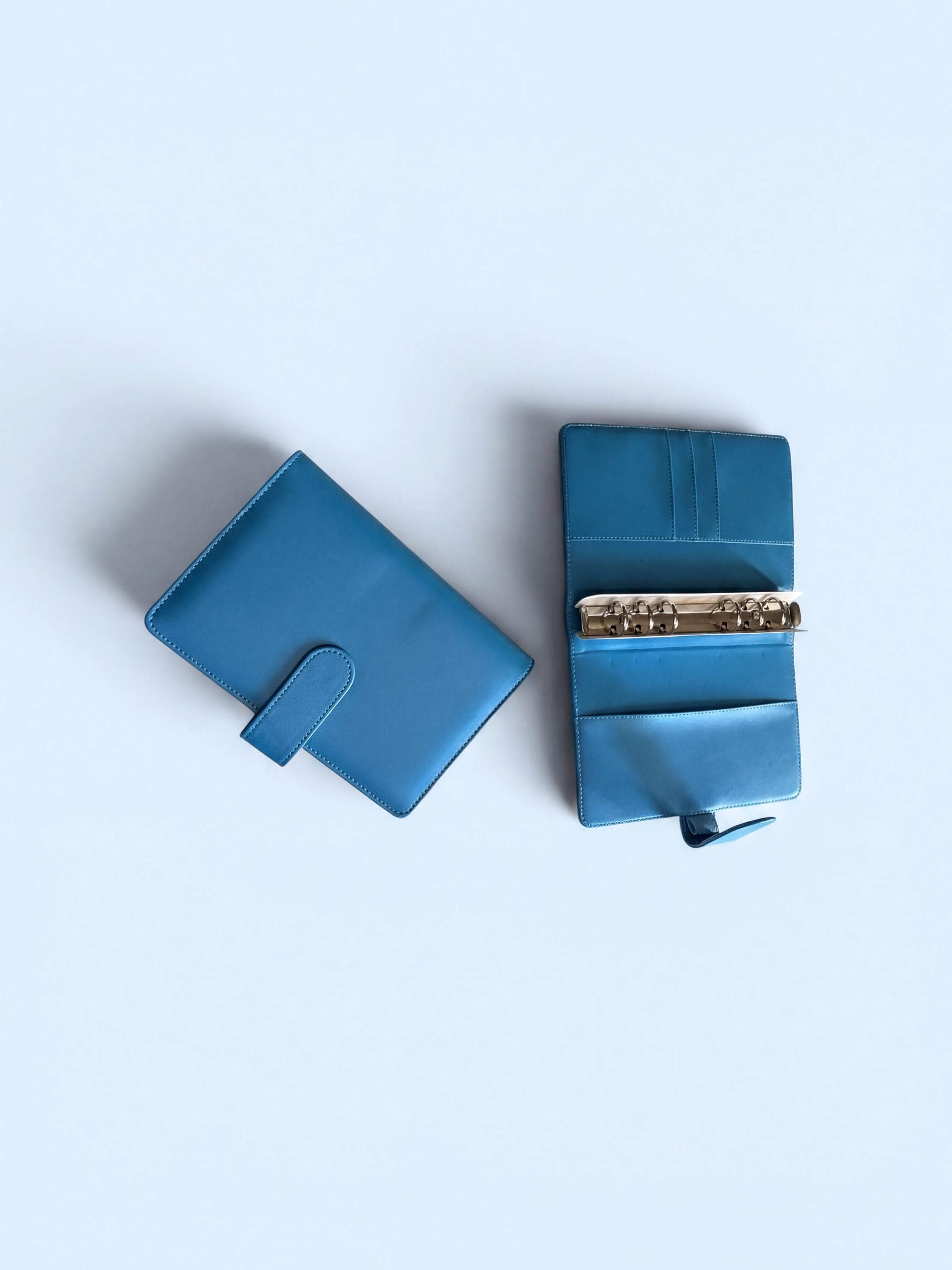 Two blue leather wallets are shown against a light blue background.