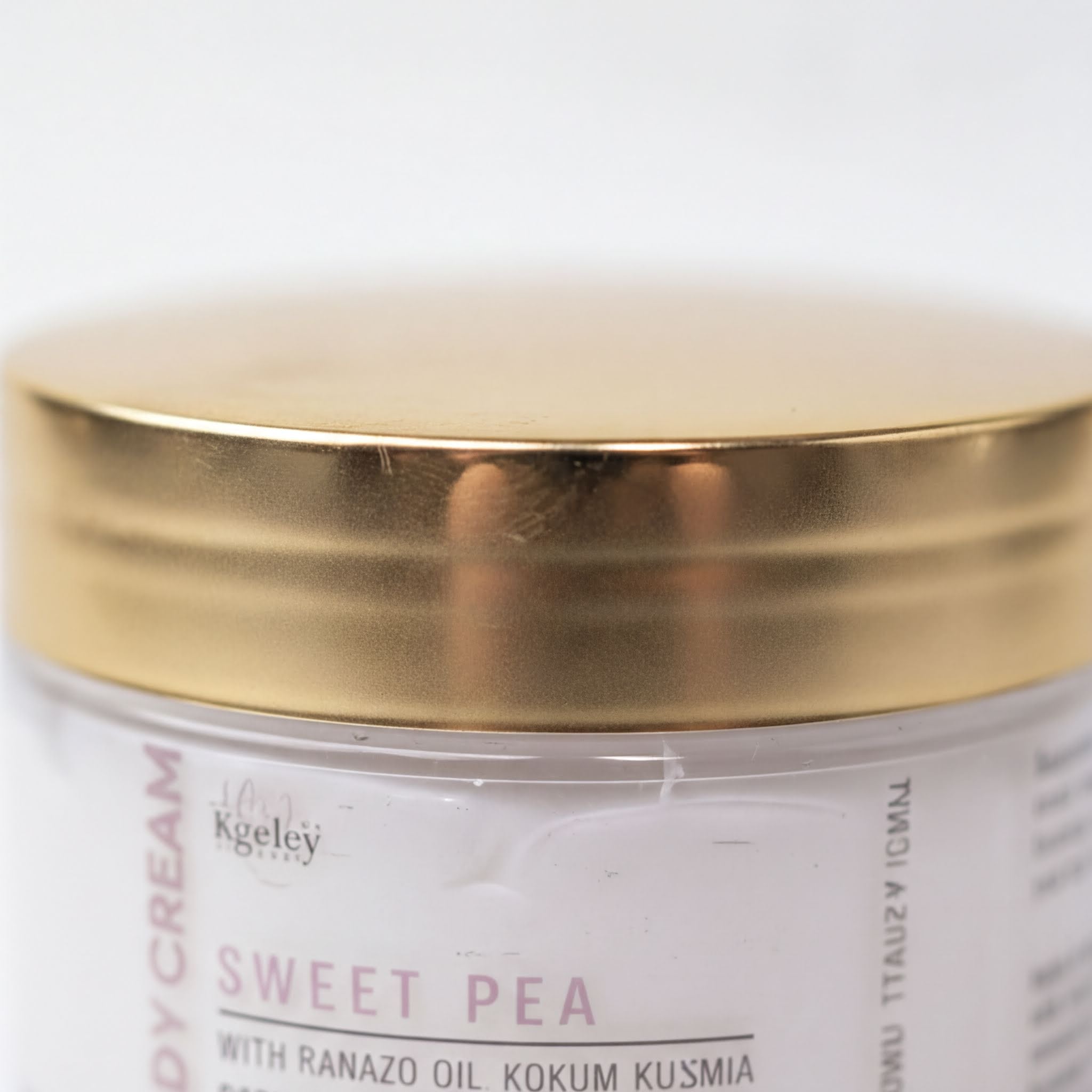 A close-up image of a jar with a gold-colored lid, featuring text and a label that reads "SWEET PEA" and "WITH RANAZO OIL KOKUM KUSMA".