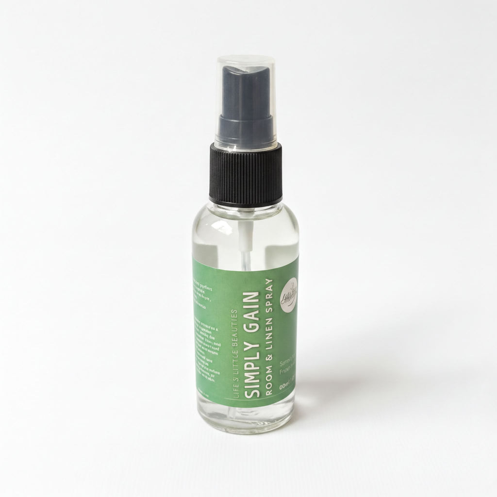 A clear glass spray bottle with a black pump, containing a clear liquid, labeled as a "Simply Gain" room spray.
