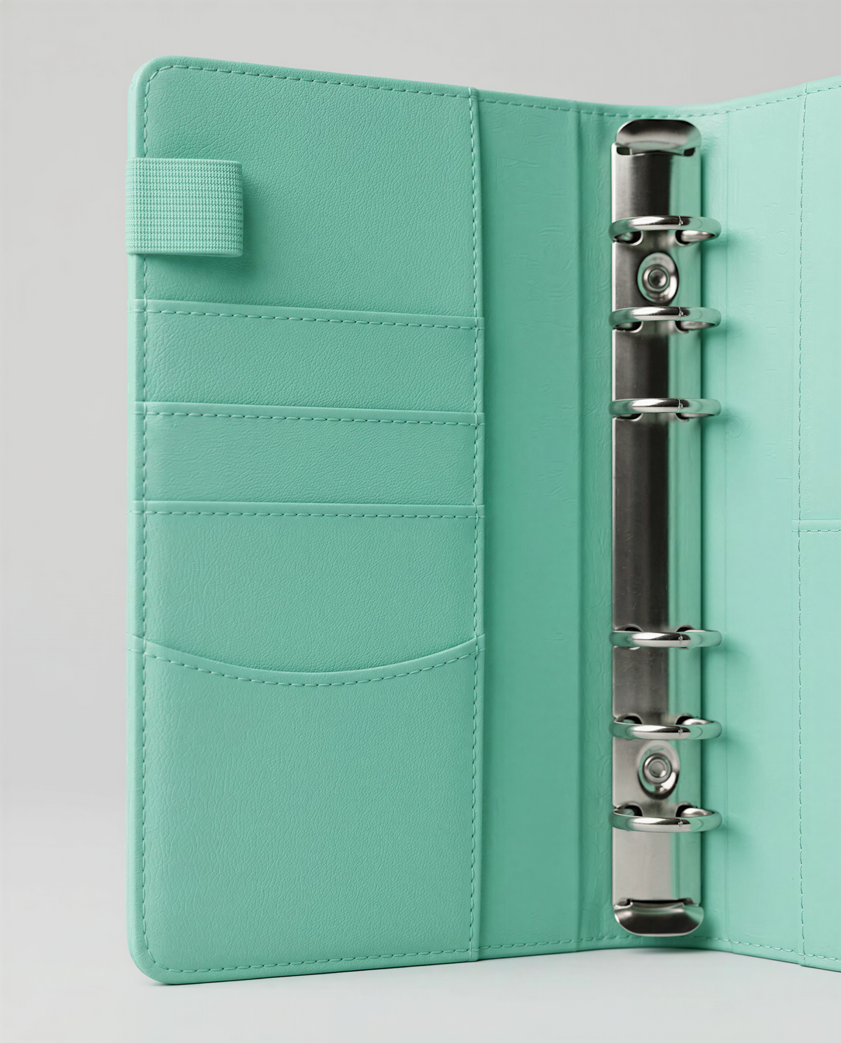 A mint green leather-like wallet or binder with multiple pockets and a metal ring mechanism.