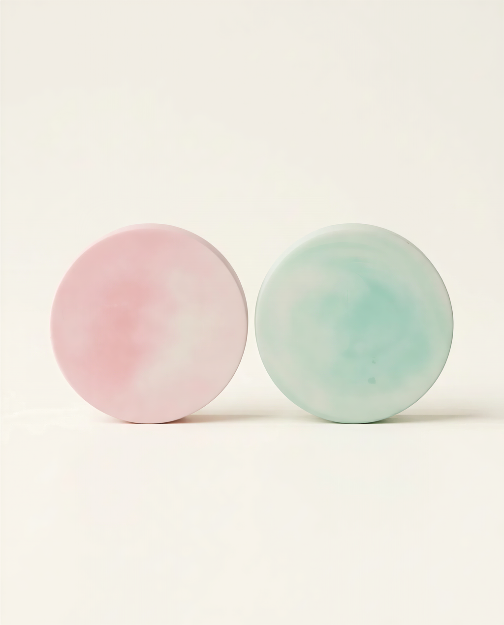 Two round objects, one pink and one green, are placed side by side against a white background.