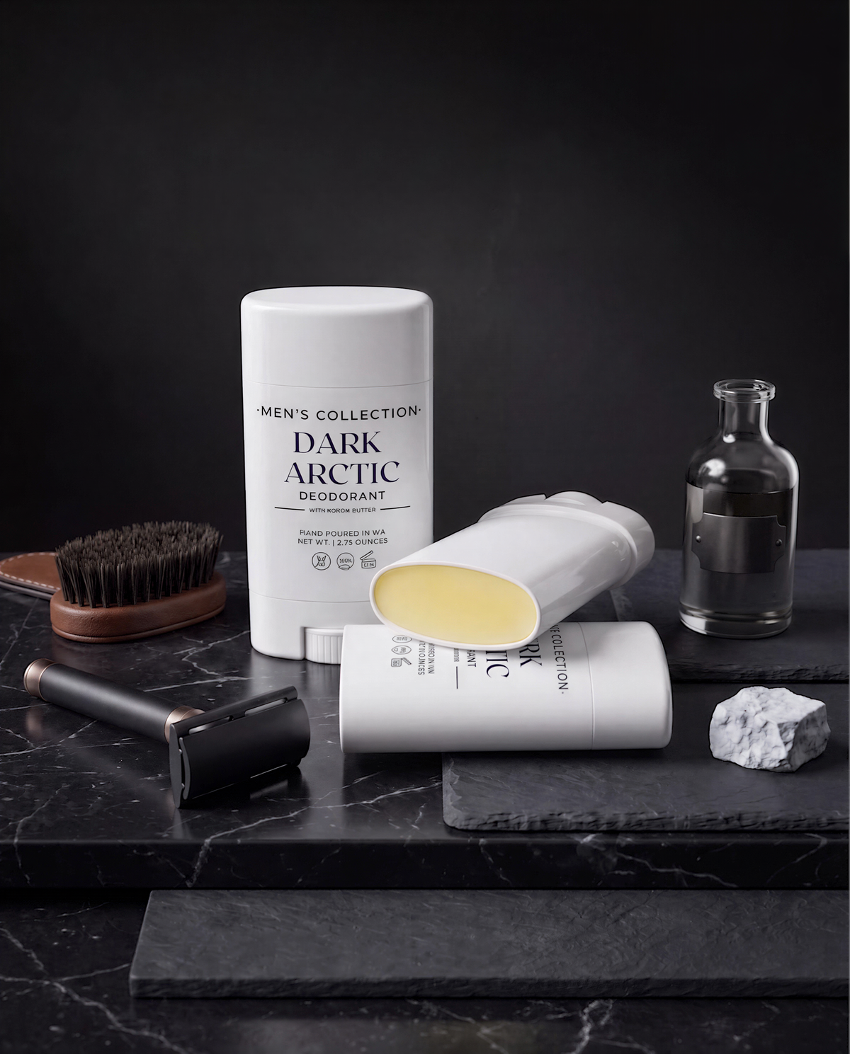 a collection of men's grooming products, including a deodorant stick, a razor, and a bottle of lotion, all arranged on a black marble surface.